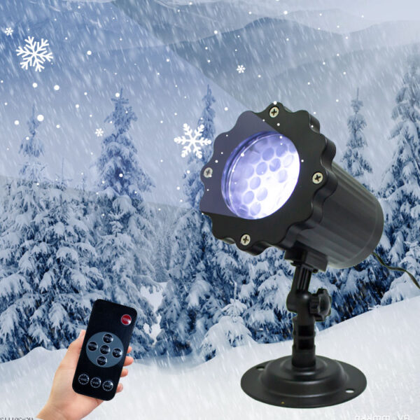 Adjustable base snowflake projection light, hand holding wireless remote control to operate lamp, snowy pine forest winter backdrop with floating white snowflake patterns, outdoor holiday decorative light product shot