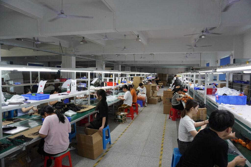 Long double-sided assembly line in LED light factory, workers assembling holiday decorative string lights