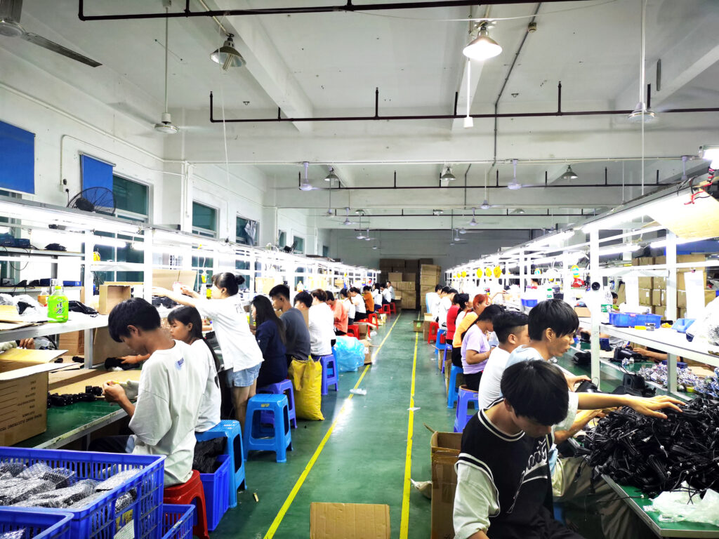 Long double-sided production line in LED decorative light factory, workers assembling string lights and projection lamps